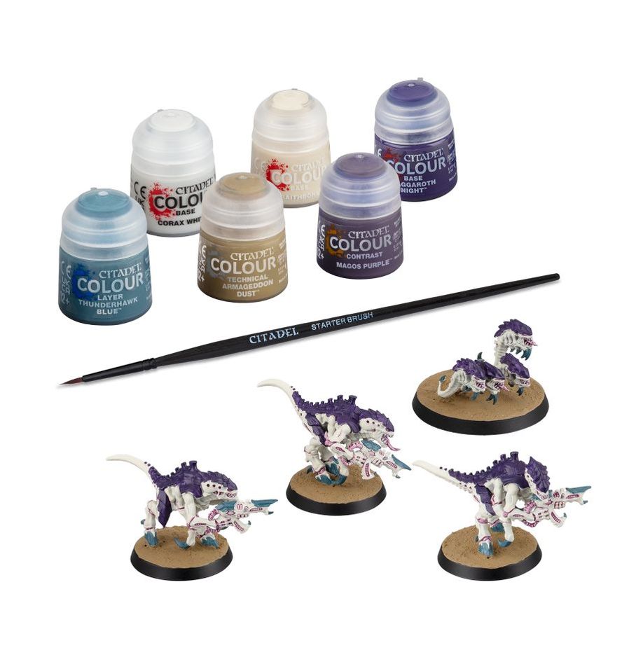 Collection of Citadel paint pots and a brush with miniatures on a white background