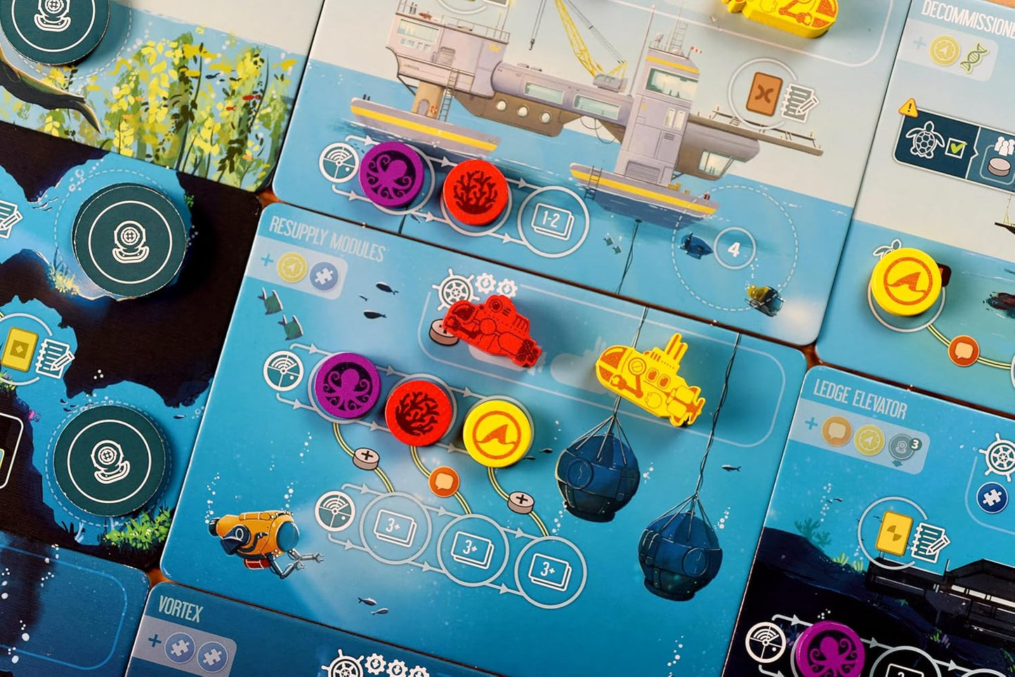 Board game components with colorful pieces and cards on a blue grid