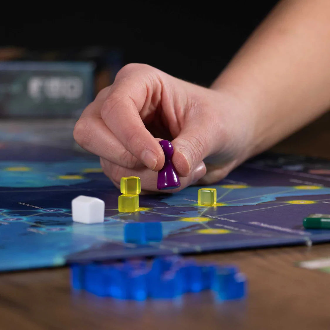 Hand playing a board game with colorful pieces on a table