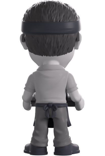 Back view of a vinyl figure of Gene Takavic from 'YouTooz' holding a tray.
