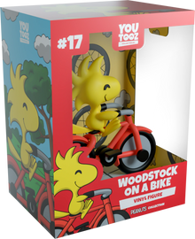 Boxed vinyl figure of Woodstock riding a bike with colorful packaging