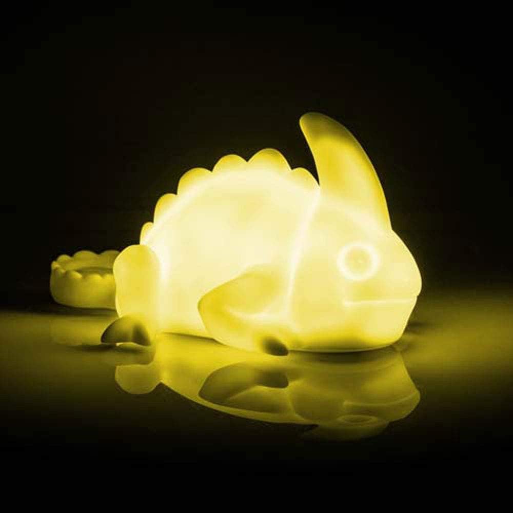 Glowing yellow dinosaur-shaped night light on a reflective surface with a dark background