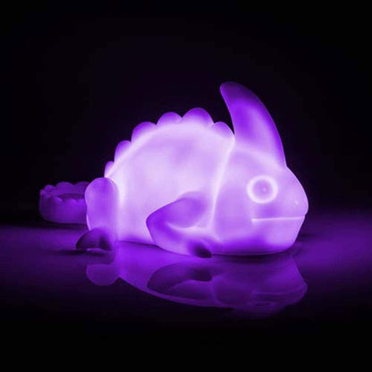 Purple dinosaur-shaped night light on a dark background