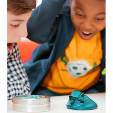 Two children playing with a blue toy putty and a small container on a white surface.
