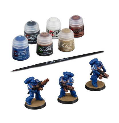  Citadel Colour paint set with miniatures and a brush on a white background