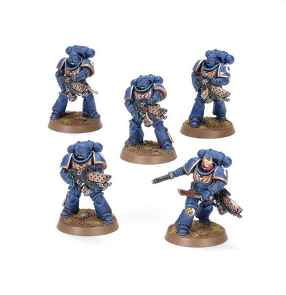 Five miniature figures in blue armor on brown bases against a white background