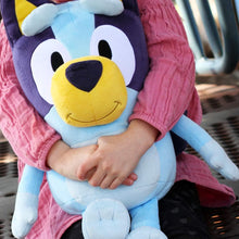 Child holding a large Bluey plush toy
