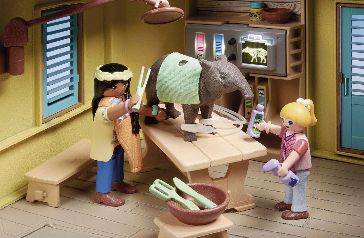 Playmobil scene with two characters and a rhino in a room with a television.