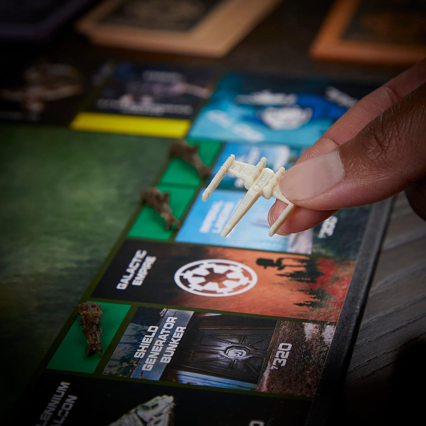 Hand holding a small model of a spaceship over a board game with game cards and pieces.