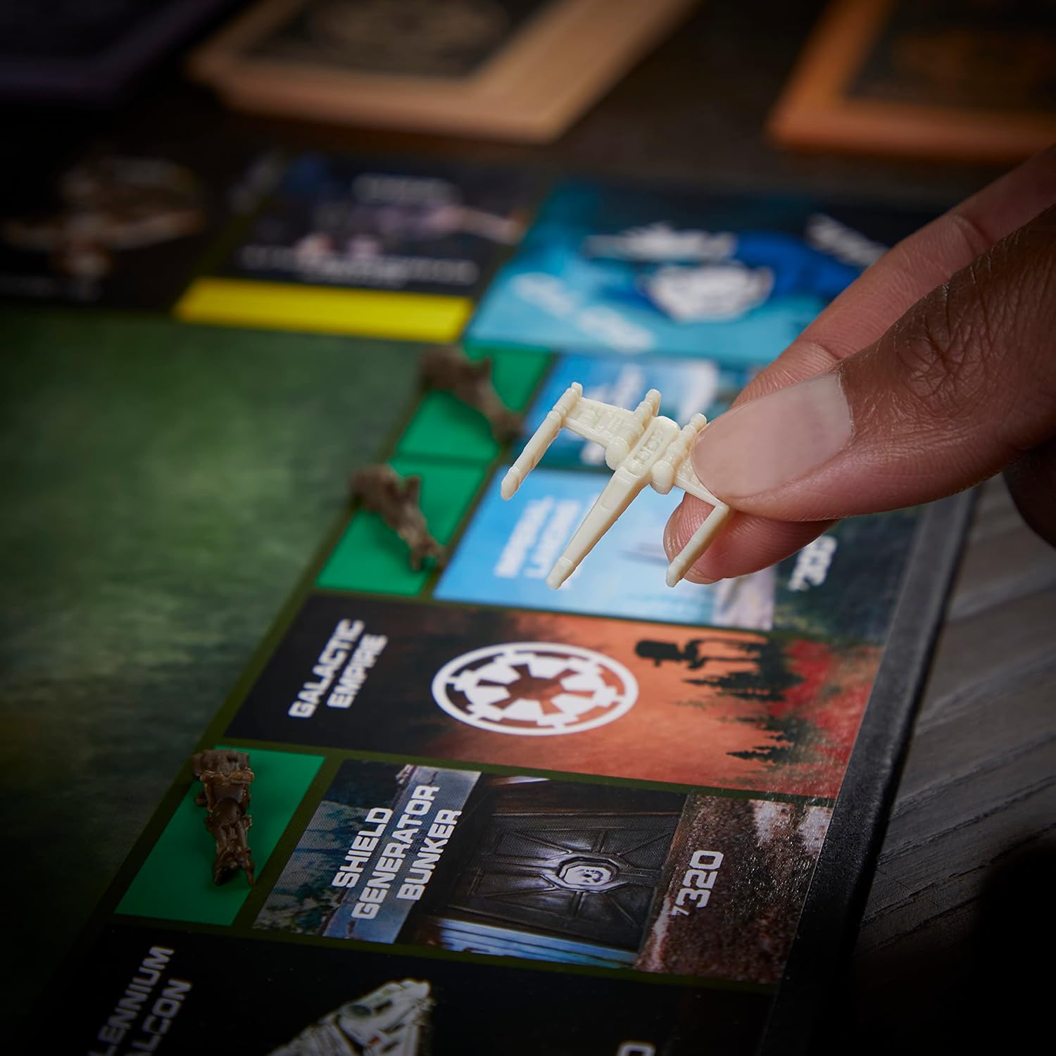 Hand holding a small model of a spaceship over a board game with game cards and pieces.