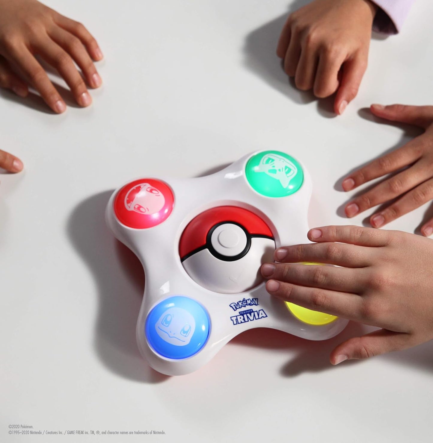 Children's hands interacting with a Poké Ball-themed toy on a white surface