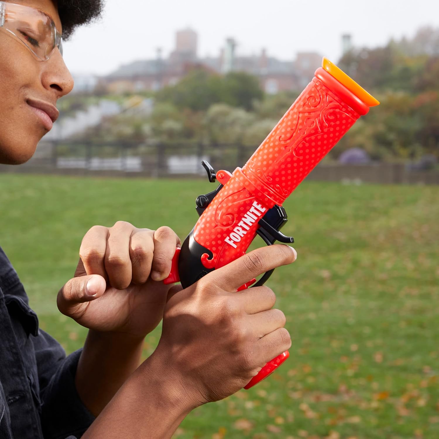 Person holding a red 'Fortnite' toy gun outdoors