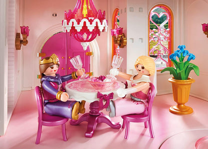 Two toy figures in a princess-themed room with a pink chandelier and furniture.