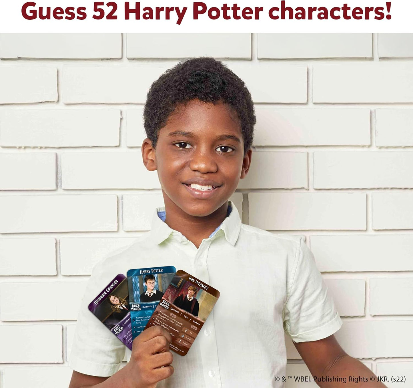 Child holding Harry Potter character cards against a white brick wall