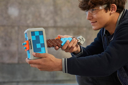 Person holding a toy device with a screen and building block attachments against a blurred background