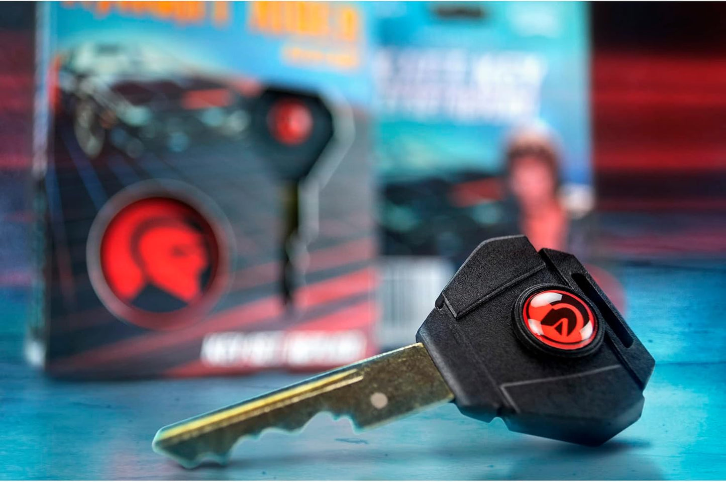 Key with a red logo on a blue surface, with a blurred product packaging in the background.