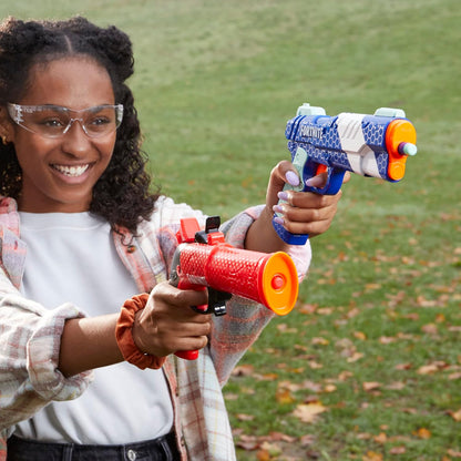 Girl holding two water guns outdoors on a grassy field