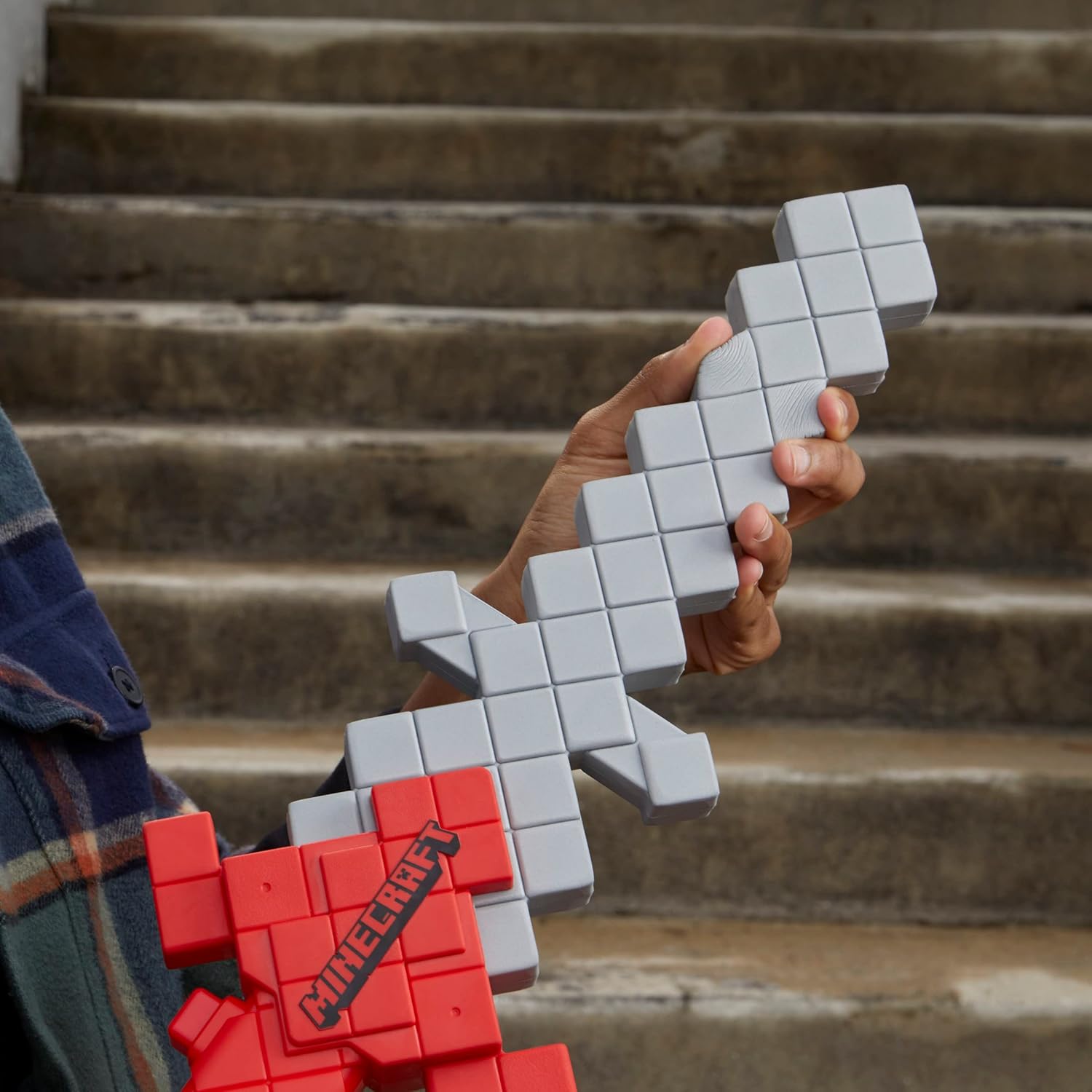 Person holding a red and gray Minecraft-themed sword against a staircase background