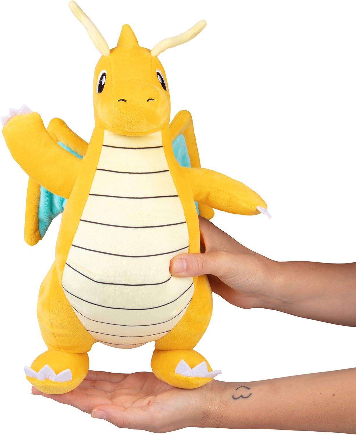 Dragonite Plush toy resembling a dragon-like creature held by a person on a white background