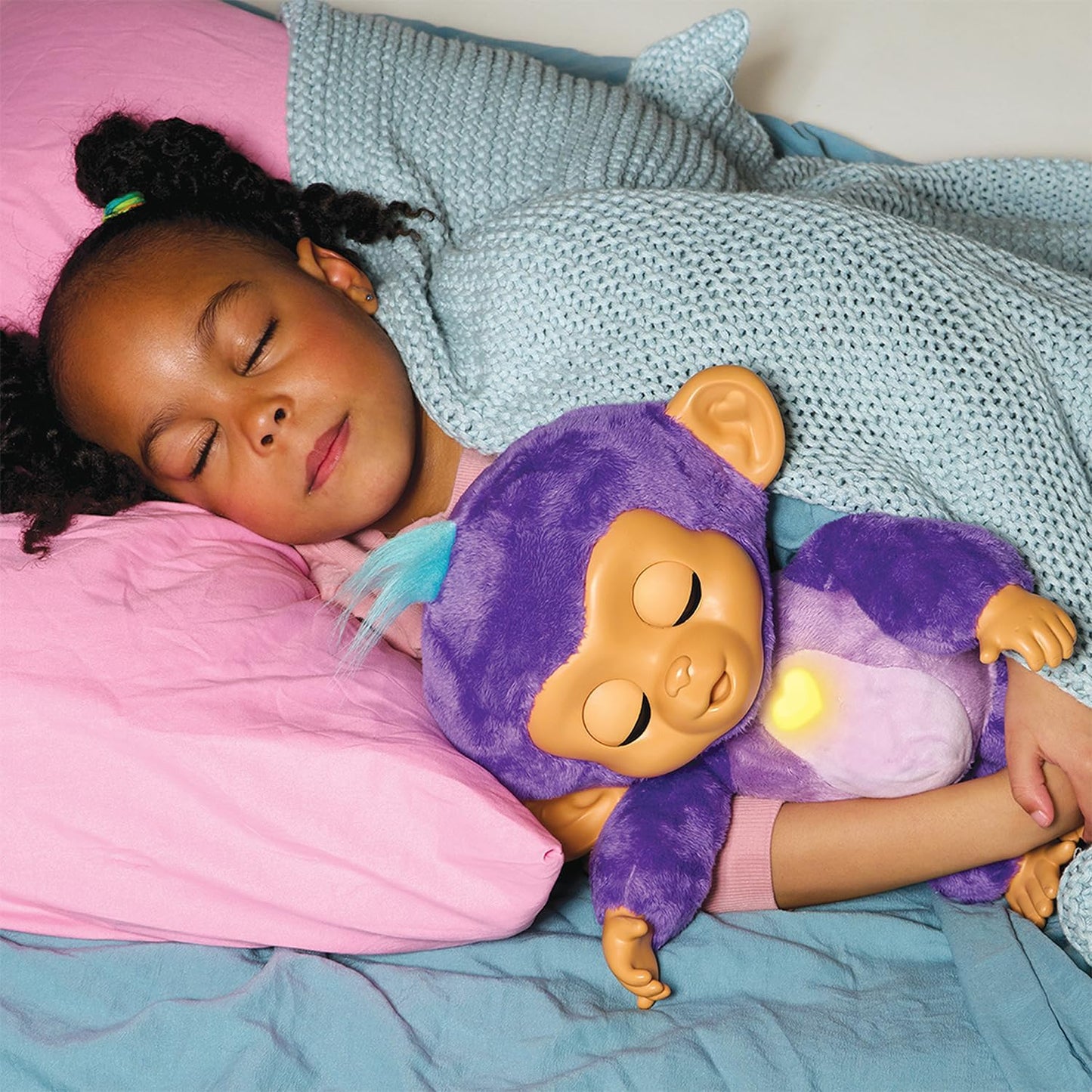 Child sleeping with a purple monkey plush toy on a bed