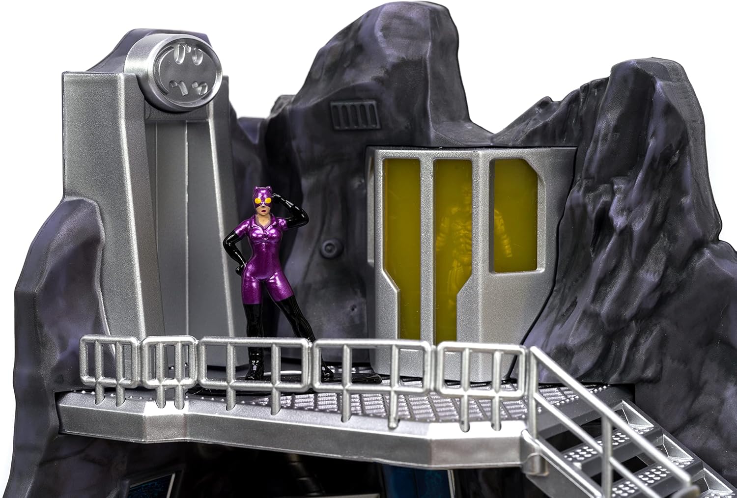Toy figure in a purple outfit standing on a metallic platform with rocky background
