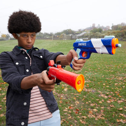 Person holding two toy guns outdoors on a grassy field