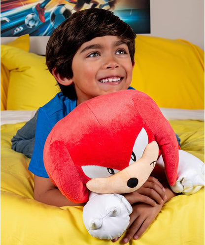 Child holding a Knuckles plush toy with a cartoon character on a yellow bed