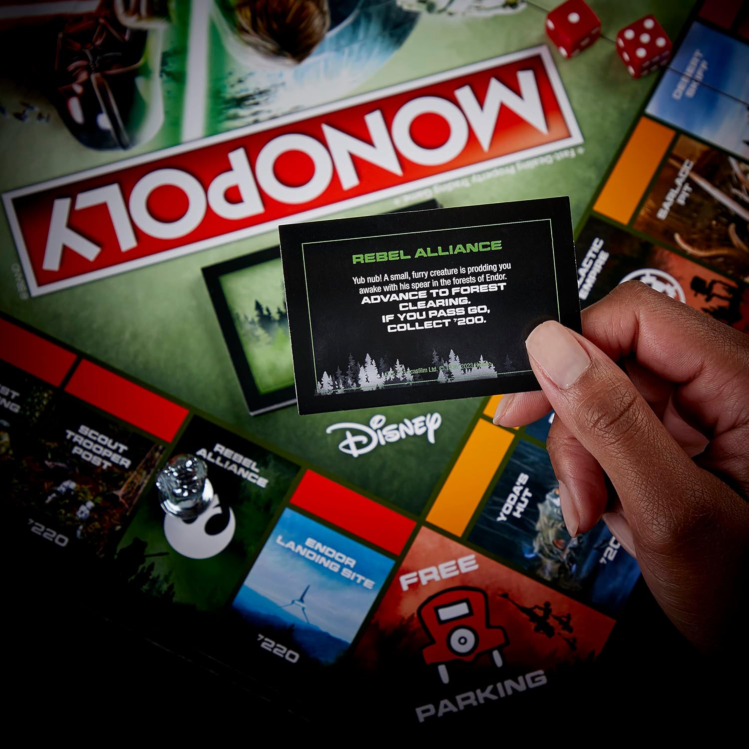 Monopoly game board with a hand holding a card featuring 'Rebel Alliance' from Star Wars.
