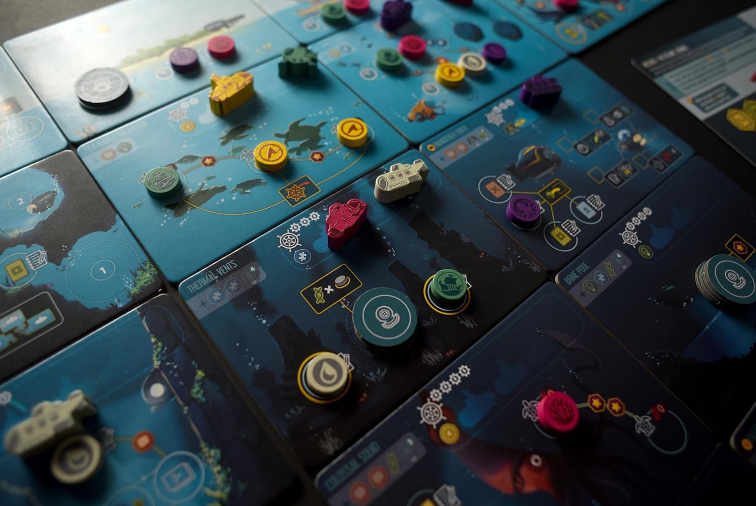 Close-up of a board game with colorful pieces on blue game boards.