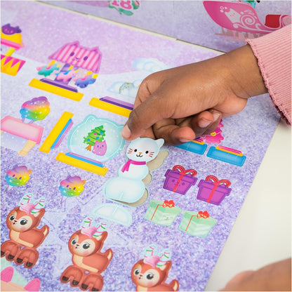 Hand placing a sticker of a cat in a snow globe on a sheet with various stickers.