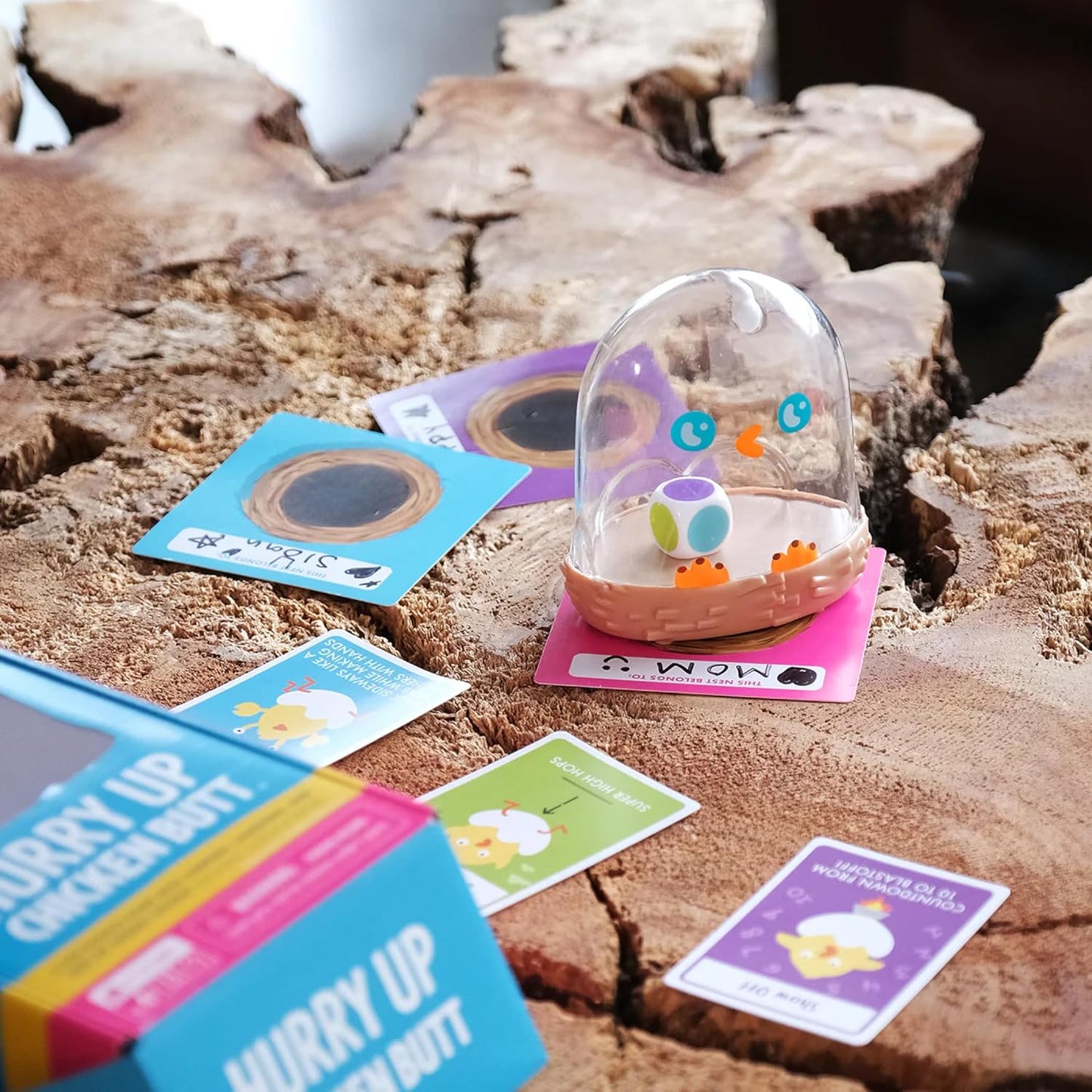 Small transparent container with a colorful object on a wooden surface with cards around it