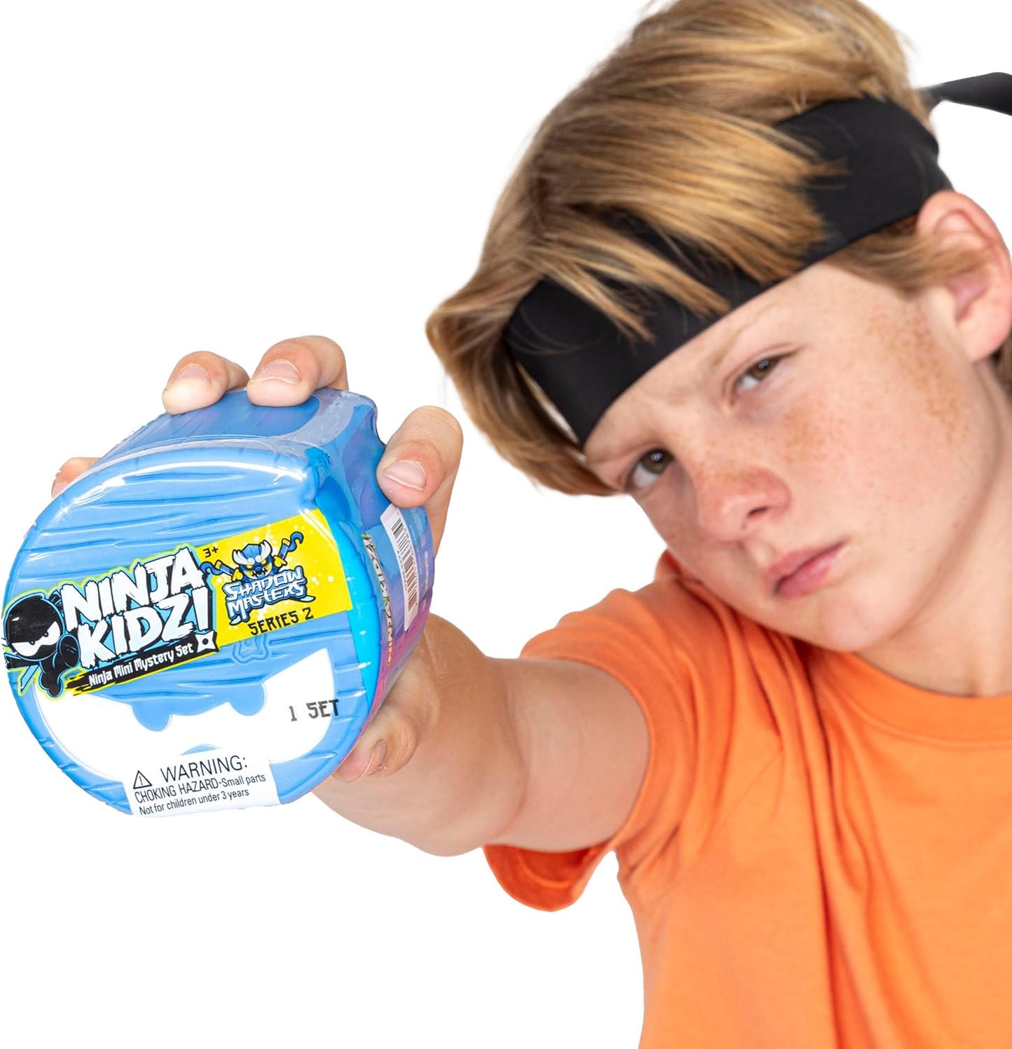 Child holding a blue 'Ninja Kidz!' toy packaging with a white background