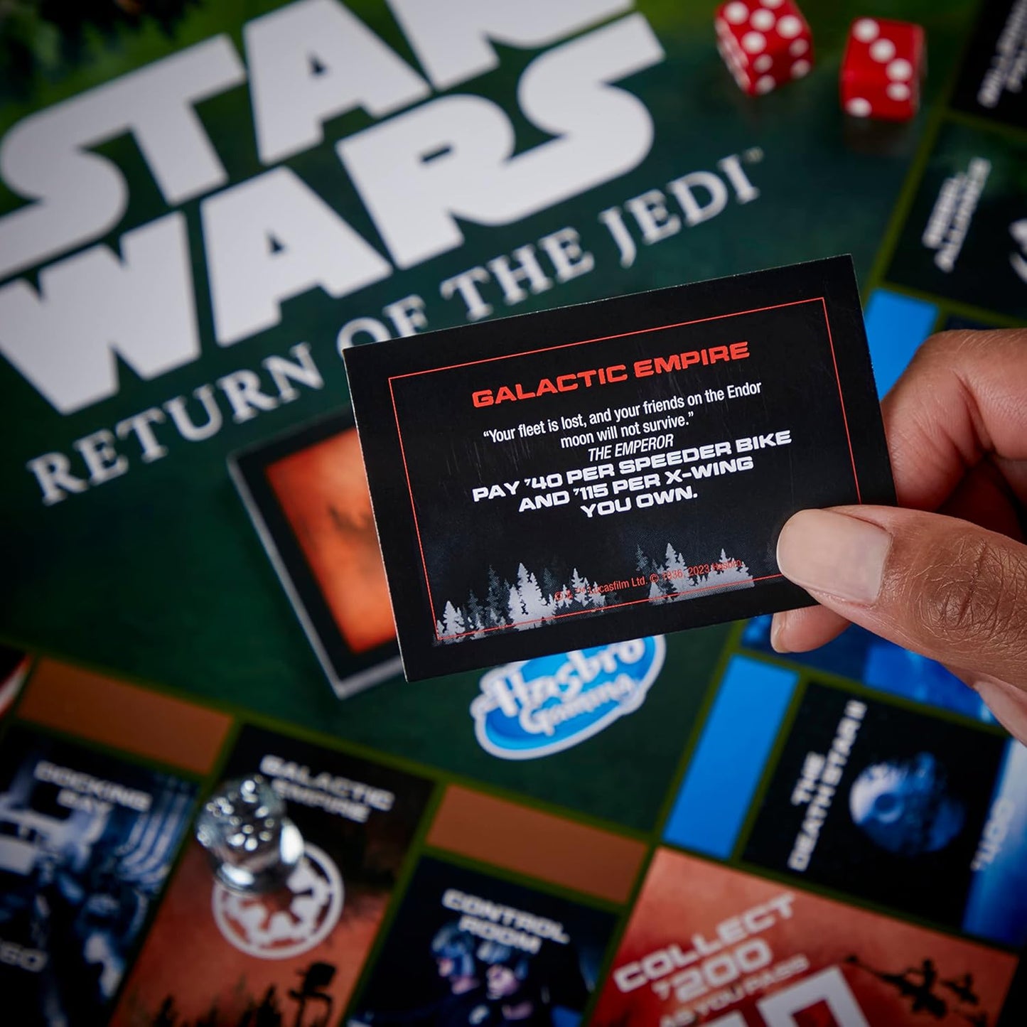 Hand holding a card from a 'Star Wars' themed board game with game pieces and text in the background.