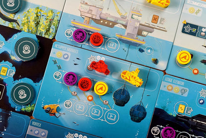 Board game components with colorful pieces and cards on a blue grid