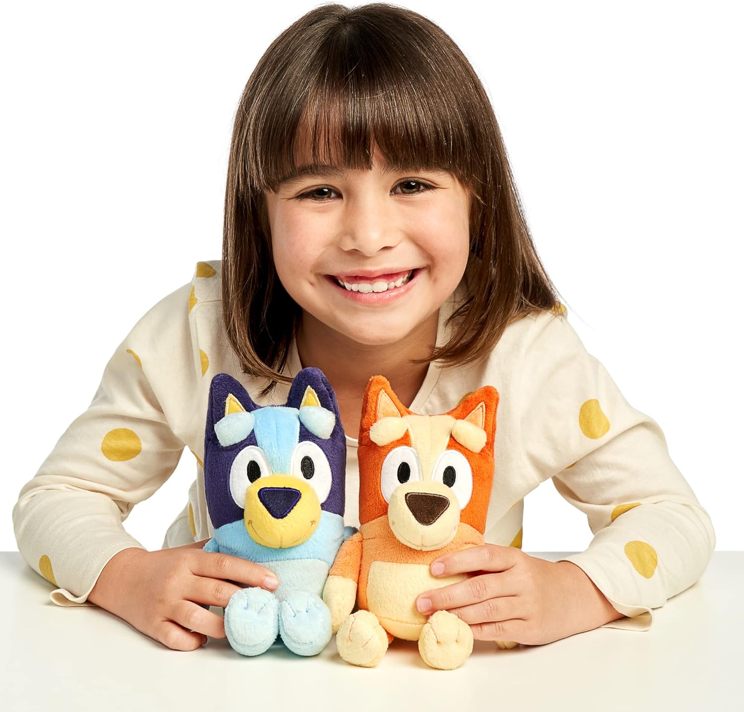Child holding two plush toys Bluey / Bingo against a white background