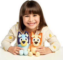 Child holding two plush toys Bluey / Bingo against a white background