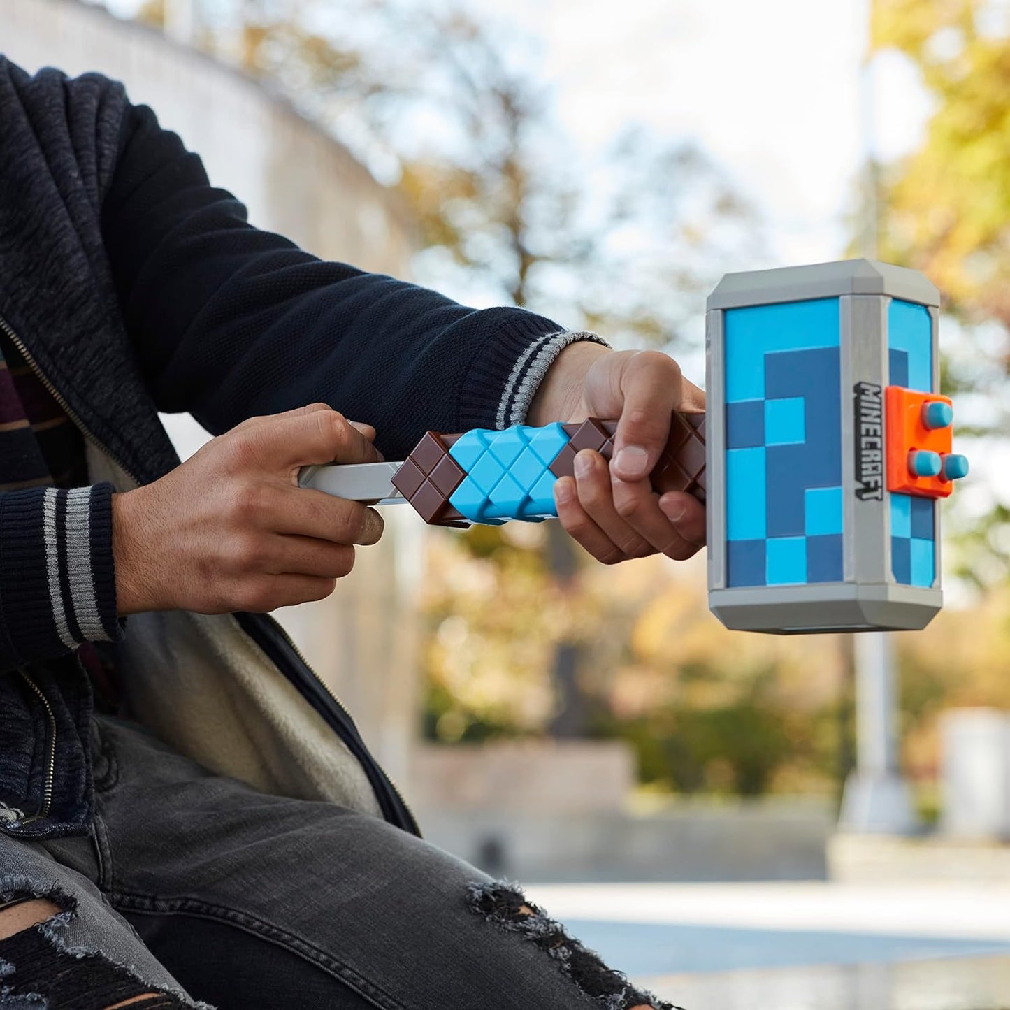 Two hands holding pixelated sword and shield against a blurred outdoor background