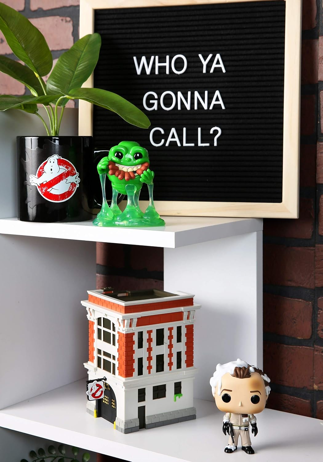 Shelf with a Ghostbusters-themed building, green figurine, and letter board with text.