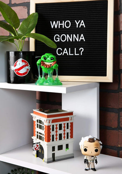 Shelf with a Ghostbusters-themed building, green figurine, and letter board with text.