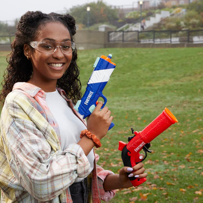 Person holding two water guns in a grassy outdoor area