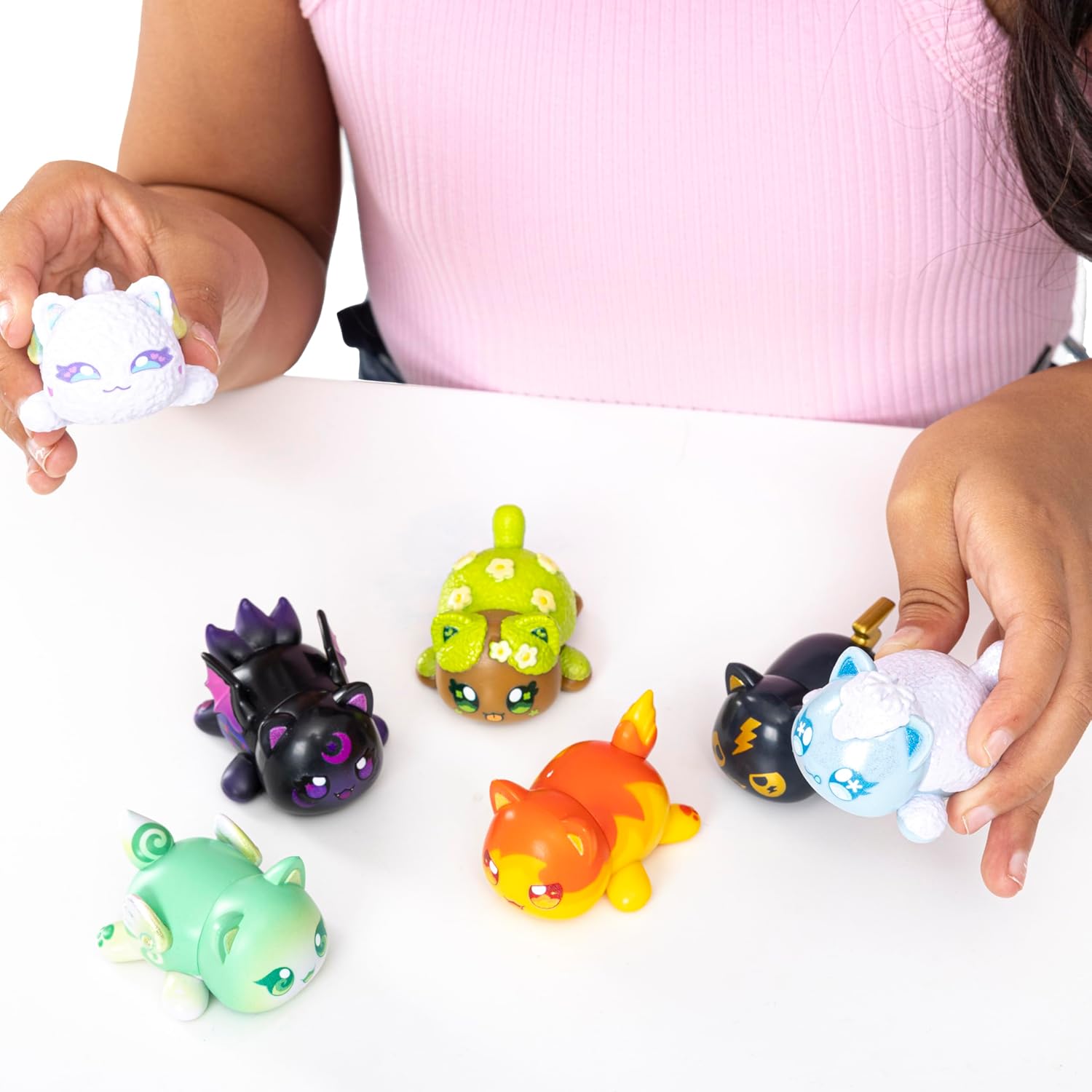 Children playing with small Aphmau figurines on a white surface