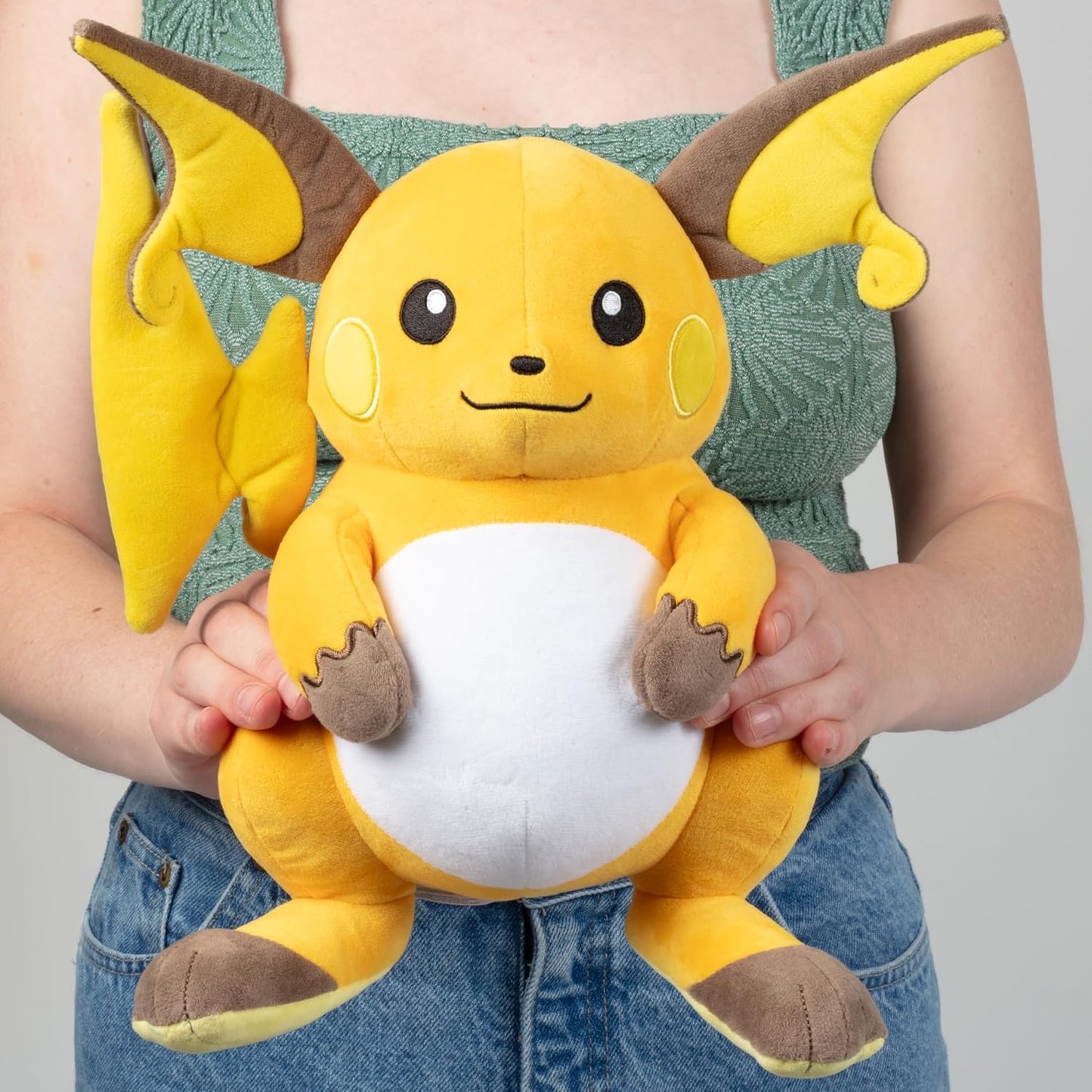 Person holding a yellow plush toy with brown accents