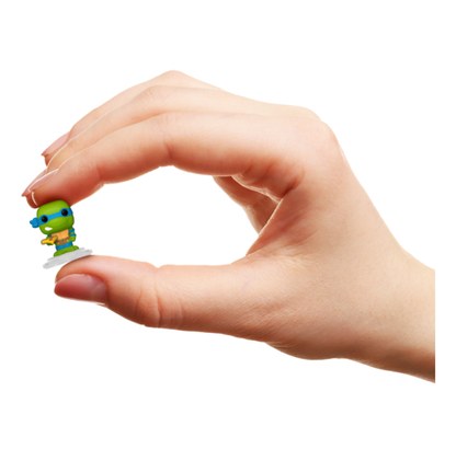 Hand holding a small green figurine against a white background