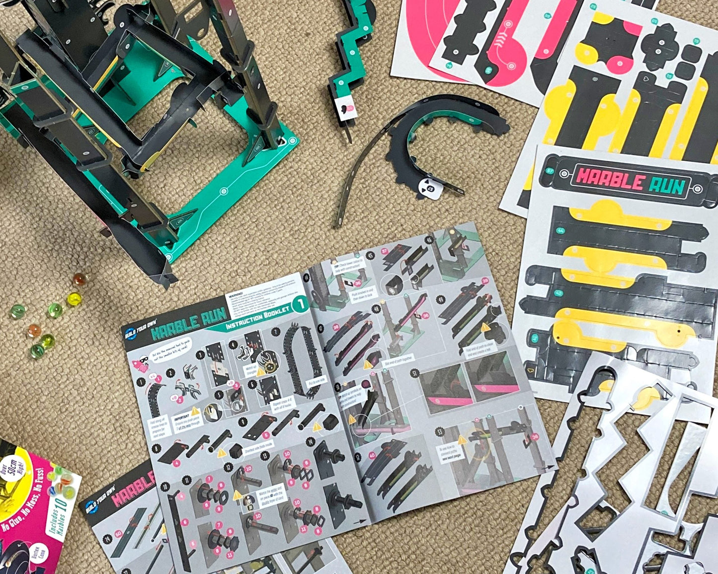 Children's toy construction set with pieces and manuals on a carpeted floor