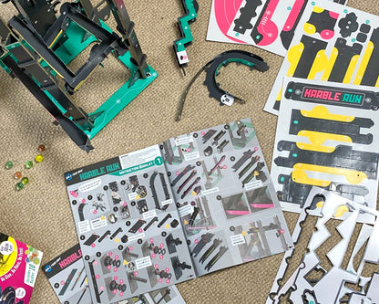 Children's toy construction set with pieces and manuals on a carpeted floor