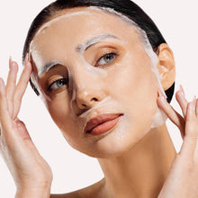 Woman applying a facial mask with a neutral background