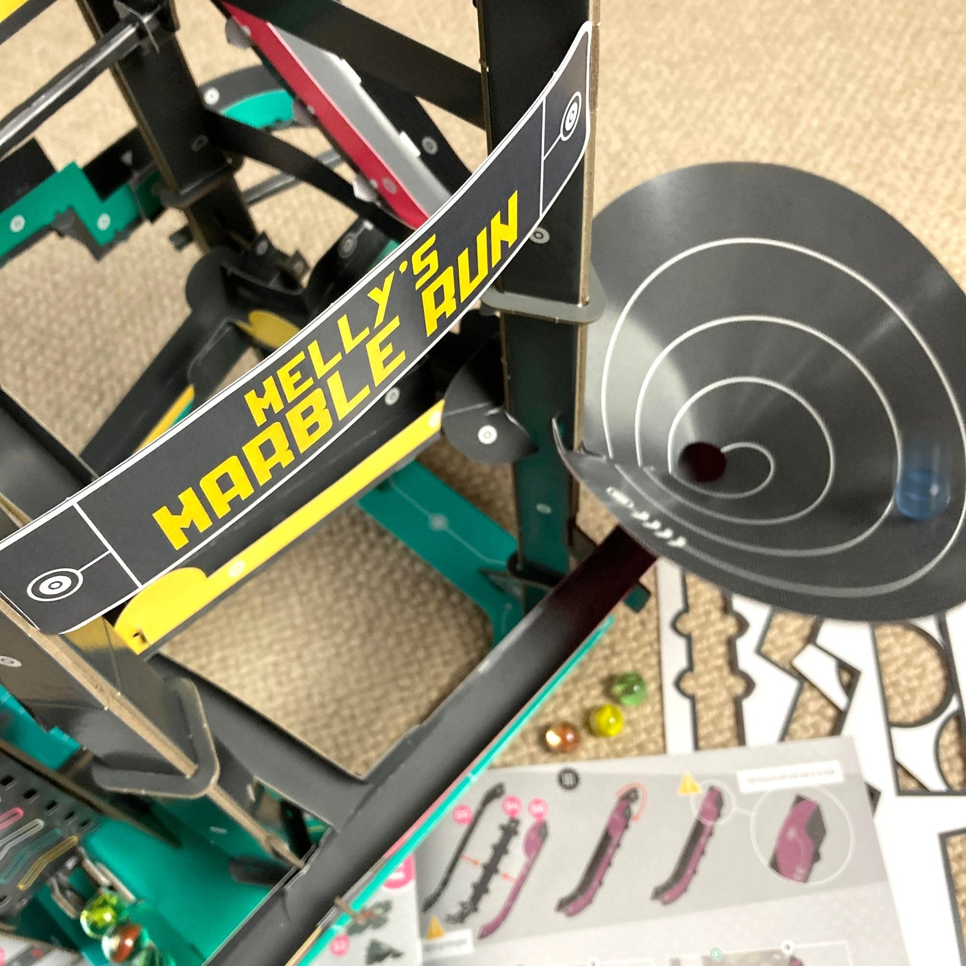Marble run toy set with 'Helly's Marble Run' branding on a carpeted floor.