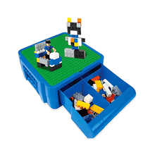 Blue toy storage box with LEGO pieces and a small model on a white background