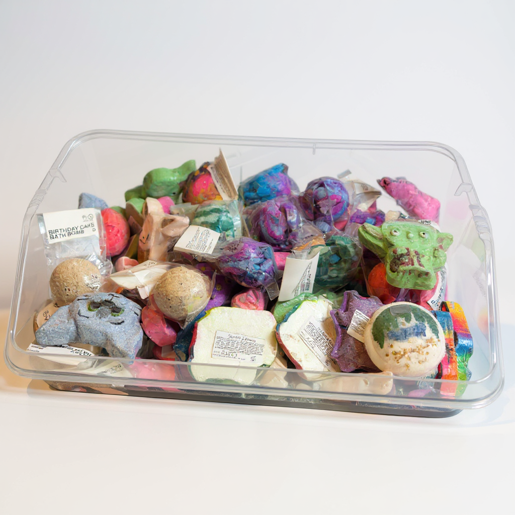 Assorted colourful bath bombs in a clear plastic container on a white background