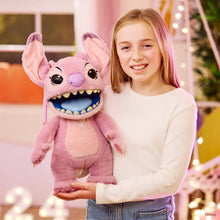 Girl holding a pink plush toy with a large mouth and smiling, in a festive indoor setting.